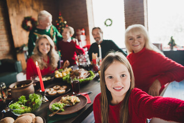 Fototapeta na wymiar Photo portrait of smiling granddaughter taking selfie of family sitting at table celebrating christmas