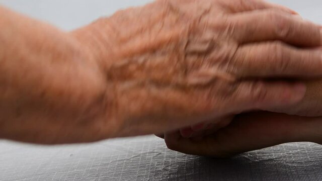 Grandmother's wrinkled hands close up. Grandmother holds the hand of an adult granddaughter. Old hands of the grandmother. Support. Seniors concept. Two generations of women are holding hands.