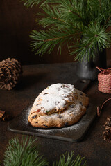 Traditional Christmas stollen on festive festive table with evergreen branches. Christmas holiday traditional dessert.