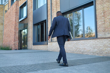 A dark-skinned man in a suit on his way to work