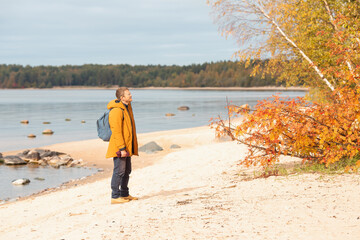 Caucasian man standing near the lake and enjoying the view. Man resting after a long walk