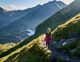 Naklejka premium Woman hiker with backpack on a trail in the mountains