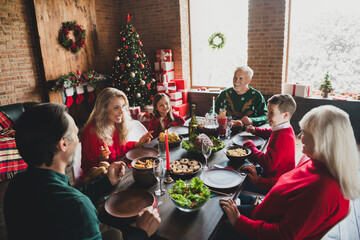 Photo portrait of full family talking sitting at festive table eating tasty dishes on xmas near decorated tree