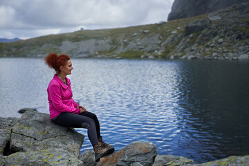 Happy woman resting after hiking by a lake