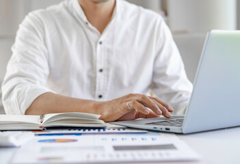 Businessman hands typing on laptop keyboard analyzing the graph at desk sales data and economic growth graph chart. Business strategy. Preparing report