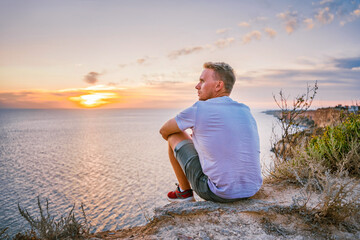 Young man admires the amazing landscape with sunset on Cape Fiolent in Crimea