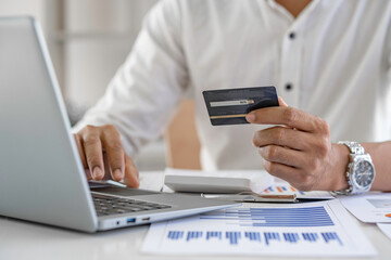 Fototapeta premium man shopping online with a credit card and laptop at table at home, Convenience online shopping