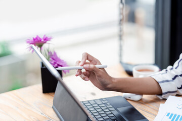 Image of a businesswoman holding a stylus working on a tablet screen at the office.