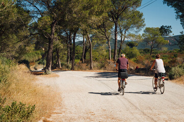 un couple de personnes âgées pédalant sur un vélo dans une forêt de Provence. Des touristes...