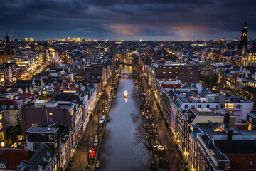 Fototapeta na wymiar Amsterdam City Canals at Night with a Tour Boat Aerial View