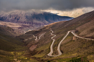 Dangerous mountain road with many turns between the mountains in an expressive cloudy day. Cuesta...