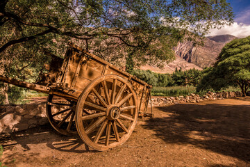Fototapeta na wymiar Big and old Horse-drawn wooden cart in a mountain landscape in Tilcara, Jujuy, Argentina. Quebrada de Humahuaca