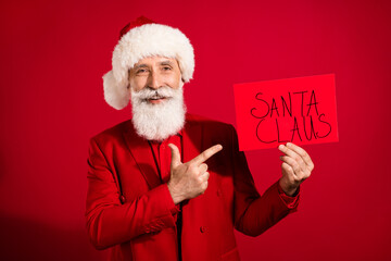 Photo of adviser santa claus finger directing sale poster wear x-mas hat suit on red color background