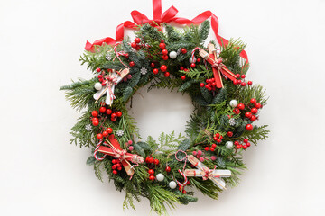 Christmas decorative wreath of natural evergreen branch with holly berries and skiing on white background. New Year. Top view. Traditional decoration for Xmas festive holiday.