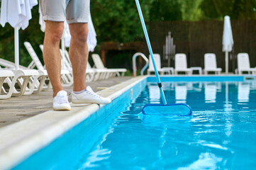 A service person cleaning the swimming pool and looking busy