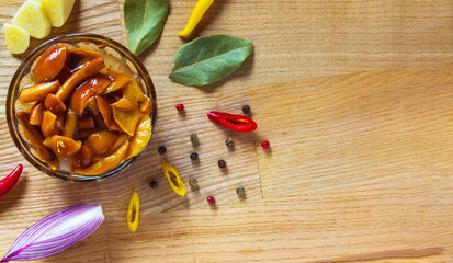 The pickled mushrooms stand on a wooden cutting board in a small glass bowl.