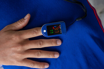 A man using pulse oximeter used to measure pulse rate and oxygen levels self at home.