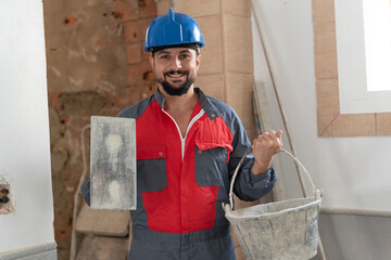bricklayer with trowel and cement basket looking at camera