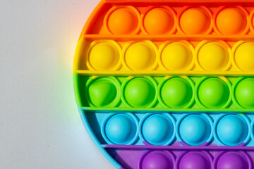 Close up round multicolored pop it toy and shadow on a white background. Colorful backdrop and copy space. 