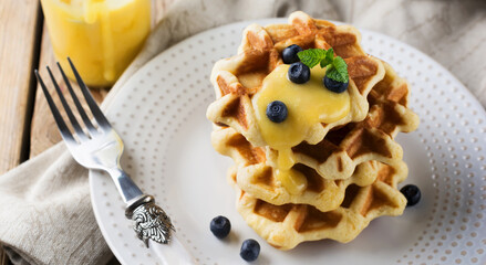 Belgian waffles with lemon Kurd and blueberries. Rustic style. Selective focus.