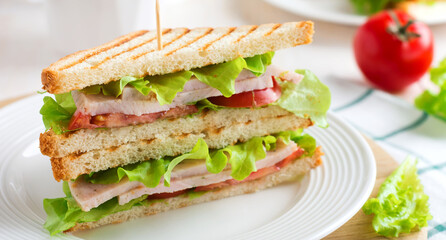 Sandwich for breakfast with stuffed tomatoes with ham and lettuce on a light wooden background. Selective focus.