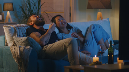 Diverse couple watching comedy film in evening - obrazy, fototapety, plakaty