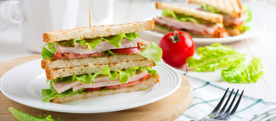 Sandwich for breakfast with stuffed tomatoes with ham and lettuce on a light wooden background. Selective focus.