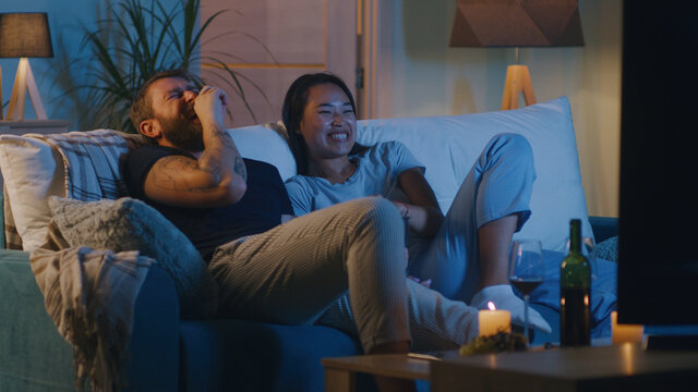 Diverse couple watching comedy film in evening