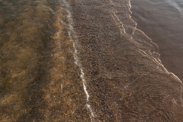 Waves with white foam and sandy shore