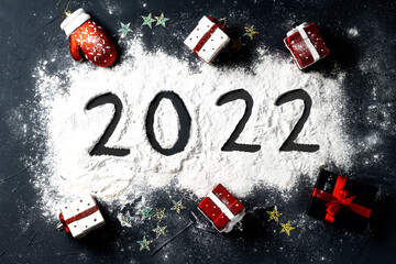 Happy New year 2022 celebration. Christmas toys present shaped and written 2022 on black background. Flat lay