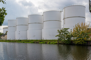 large white steel reservoirs of a tank farm for mineral oil at a canal. 