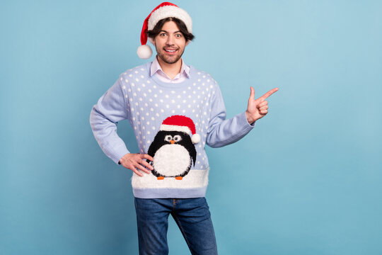 Photo of sweet charming young man dressed blue christmas pullover pointing finger empty space smiling isolated blue color background