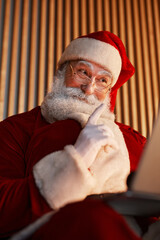 Smiling Santa Claus showing index finger while talking via video chat on tablet