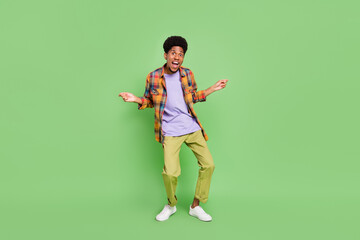 Fototapeta na wymiar Photo of impressed funny dark skin guy dressed checkered shirt dancing smiling isolated green color background