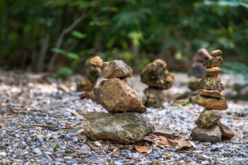 Obraz premium Balanced stone tower on walkway up the mountain with green plants in the background. Copy space, Selective focus.