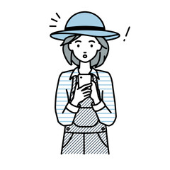 立ってスマートフォンを操作して何かに気づいて驚いた農家の女性