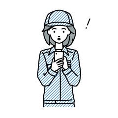 立ってスマートフォンを操作して何かに気づいて驚いた作業員の女性