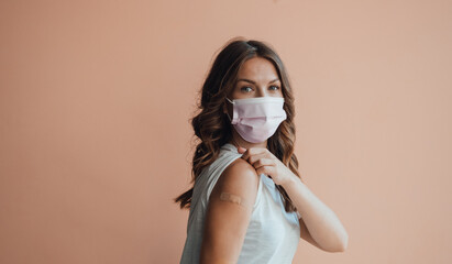Portrait of Happy Teenage Girl with Protective Face Mask Showing her Arm with a Adhesive Bandage...