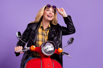 Fototapeta na wymiar Portrait of attractive cheerful dreamy wavy-haired girl riding retro moped having fun isolated over bright violet purple color background