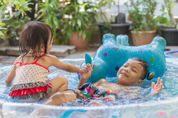 In the Summer season. Asian children swimming and playing in the the water pool.
