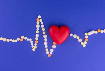 Heart of cardiograms from color pills on a blue background. Concept of heart disease.