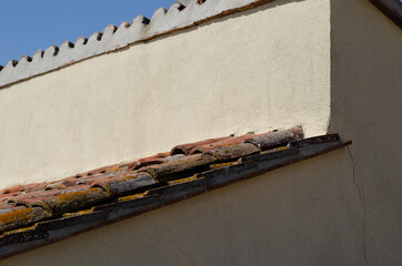 House: building with pitched roof with brick tiles, visible in the way the eaves, and front of the cornice.