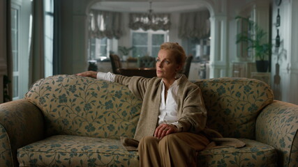 Pensive senior woman looking aside in classic interior. Serious old woman