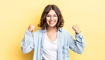 young pretty girl feeling happy, positive and successful, celebrating victory, achievements or good...