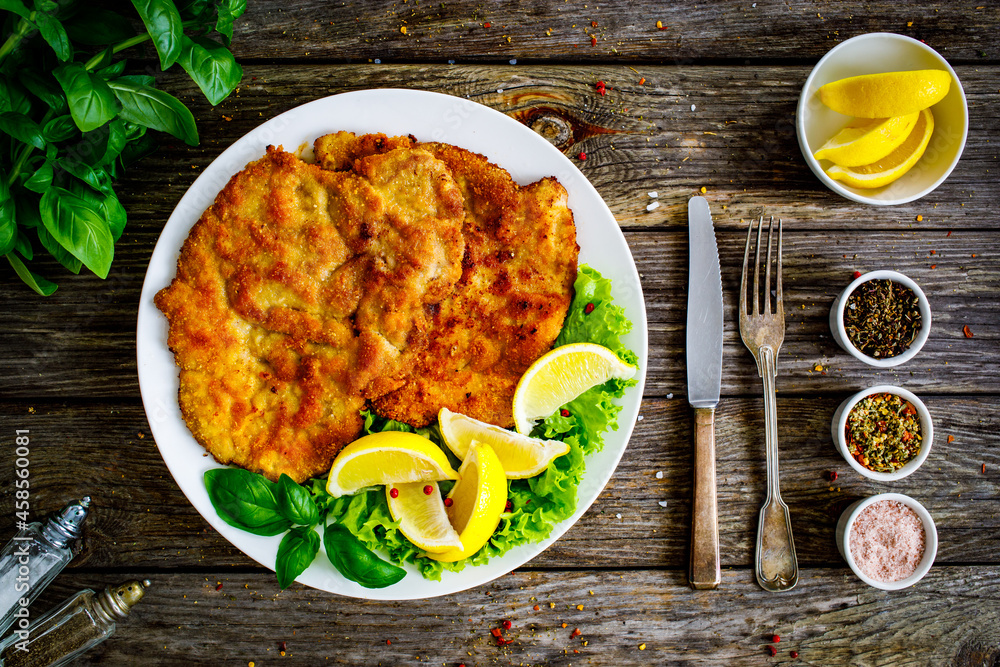 Sticker Breaded fried pork chop with lemon and fresh vegetables on wooden table
