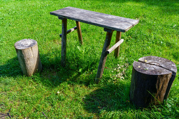 Old wooden table and tree trunks to sit in the field.