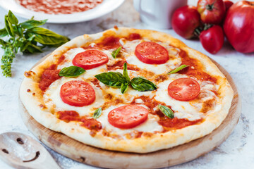 Classic Pizza with basil and tomato on top places on a bright background
