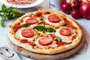 Classic Pizza with basil and tomato on top places on a bright background
