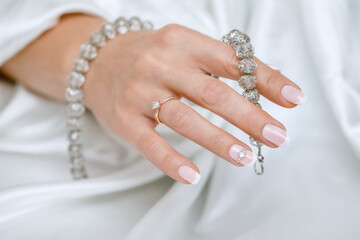 Beautiful French manicure in pink and white with rhinestones for the bride. Close-up nails. Wedding accessories.