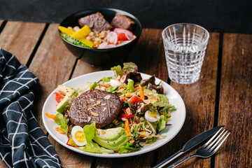 salad with juicy vegan cutlet, avocado, egg, tomato, almonds, greens, quinoa, radish, mini corn